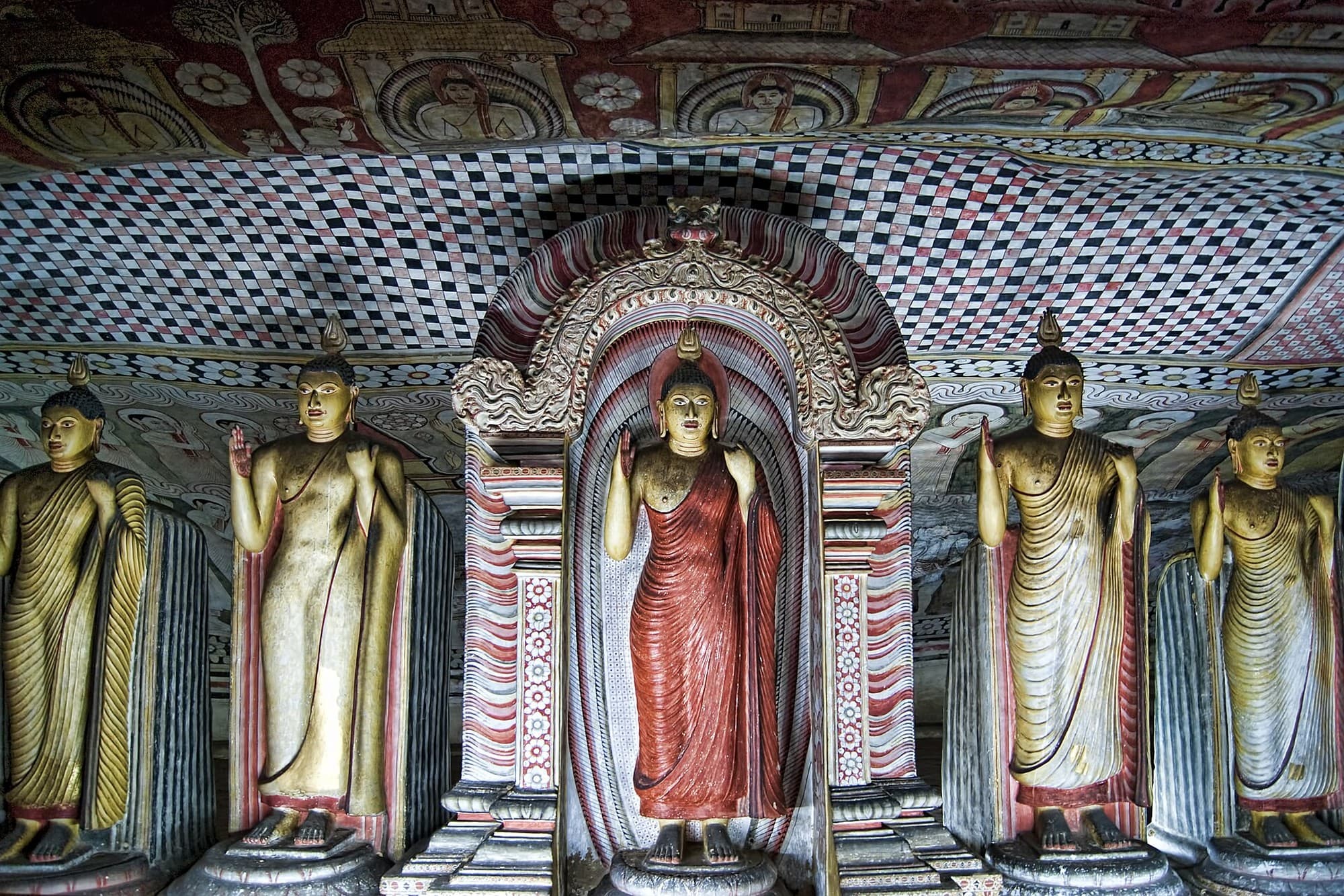 Standing Buddha statues beneath painted ceilings inside the Dambulla Cave Temple